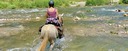 A trail rider crossing a mountain river in the Pyrenees on a Spanish horse