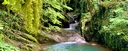 Small waterfall flowing from pool to pool with turquoise water in a forested mountain landscape