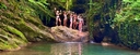 Group of happy female trail riders standing on rocks above a river pool during a riding holidayt
