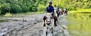 Group of trail riders crossing a river on Spanish horses during a mountain riding adventure